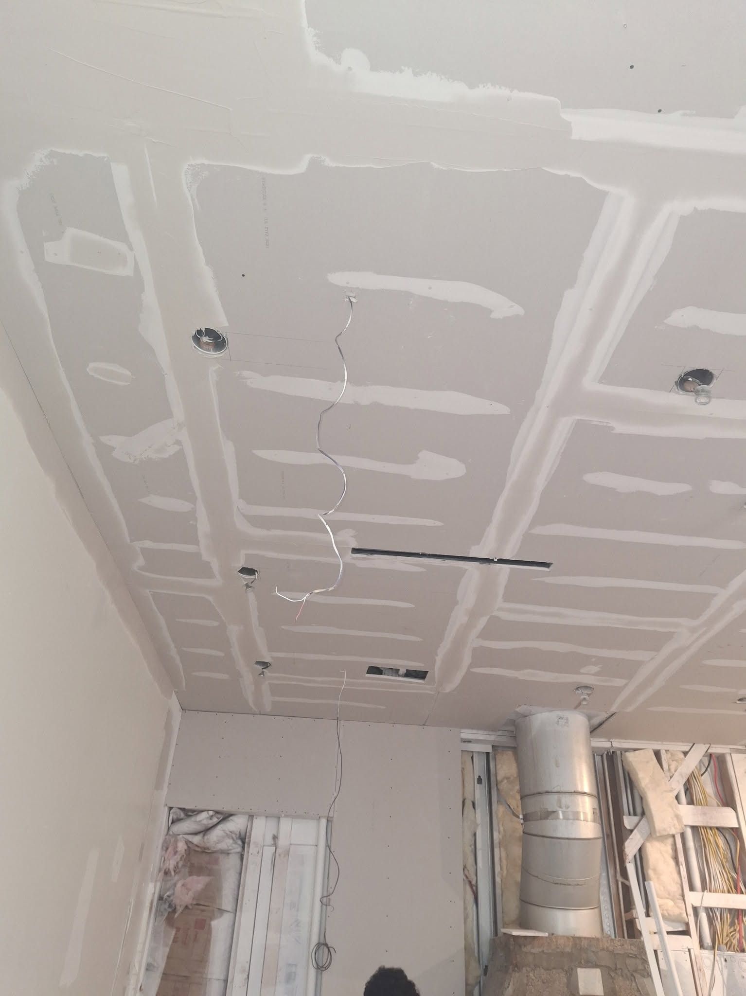 A coffered ceiling in sheetrock with mudded seams and wiring still hanging, before paint.